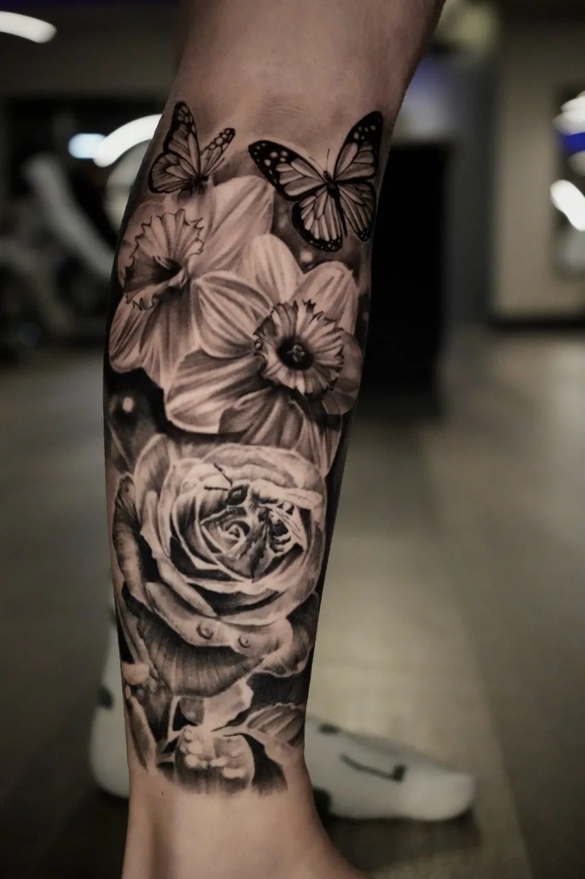 Black and grey floral and butterfly leg tattoo by Courtnie Heller