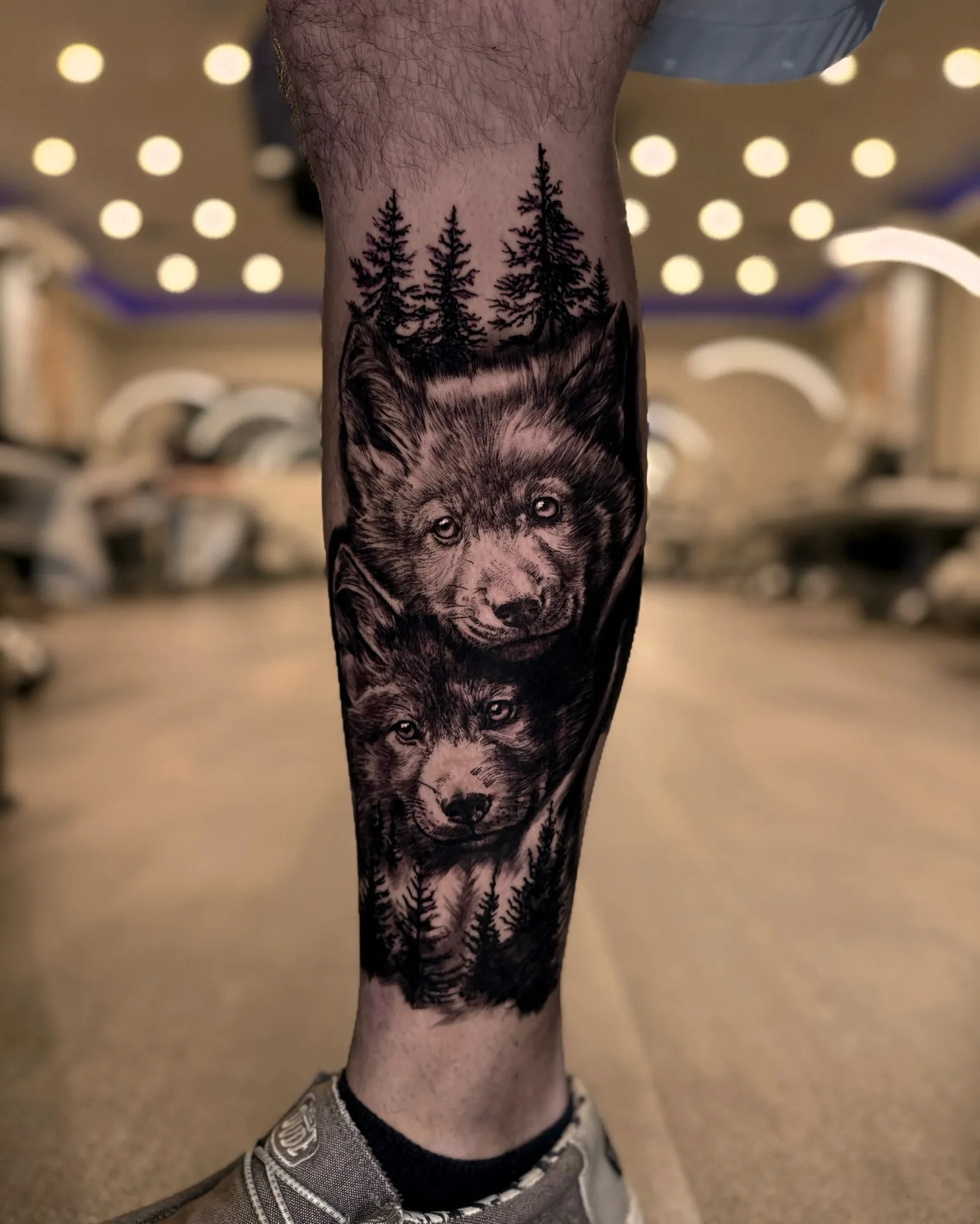 Black and grey realism wolves and pine forest leg tattoo by Zach Truitt