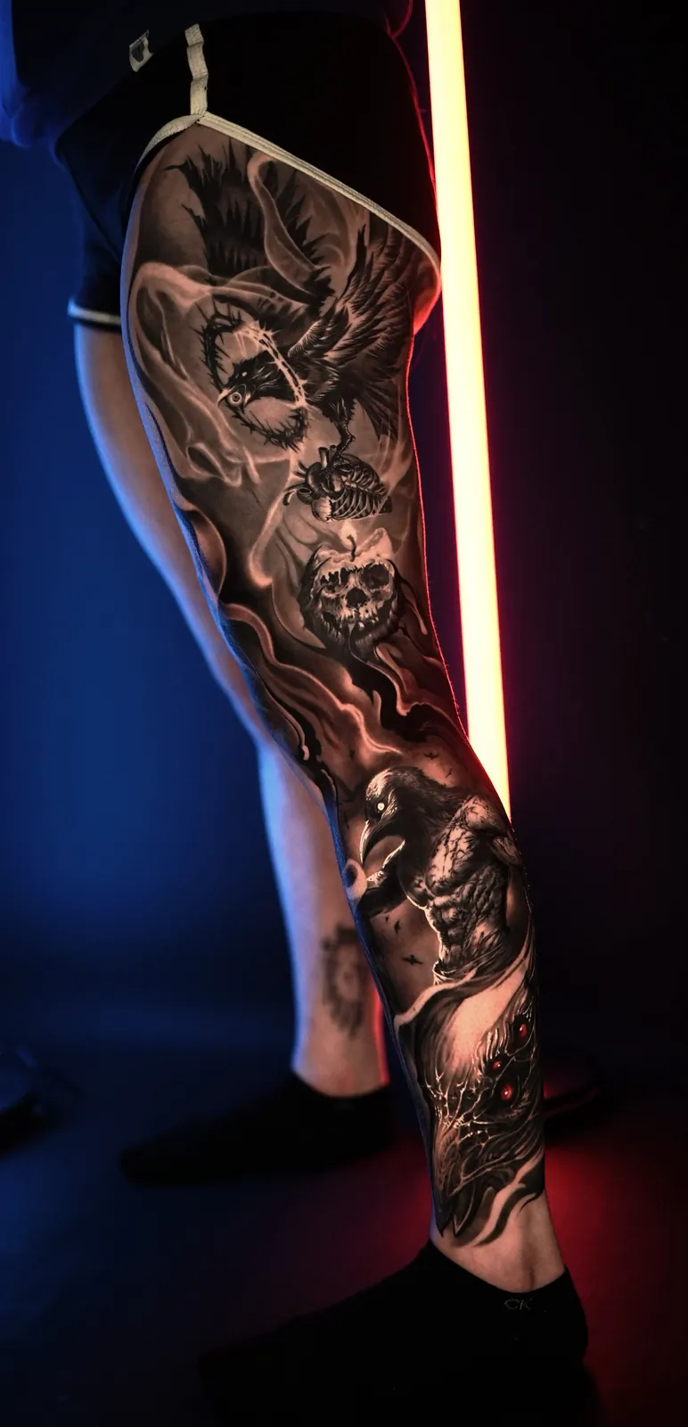 Black and grey raven and skull leg sleeve tattoo