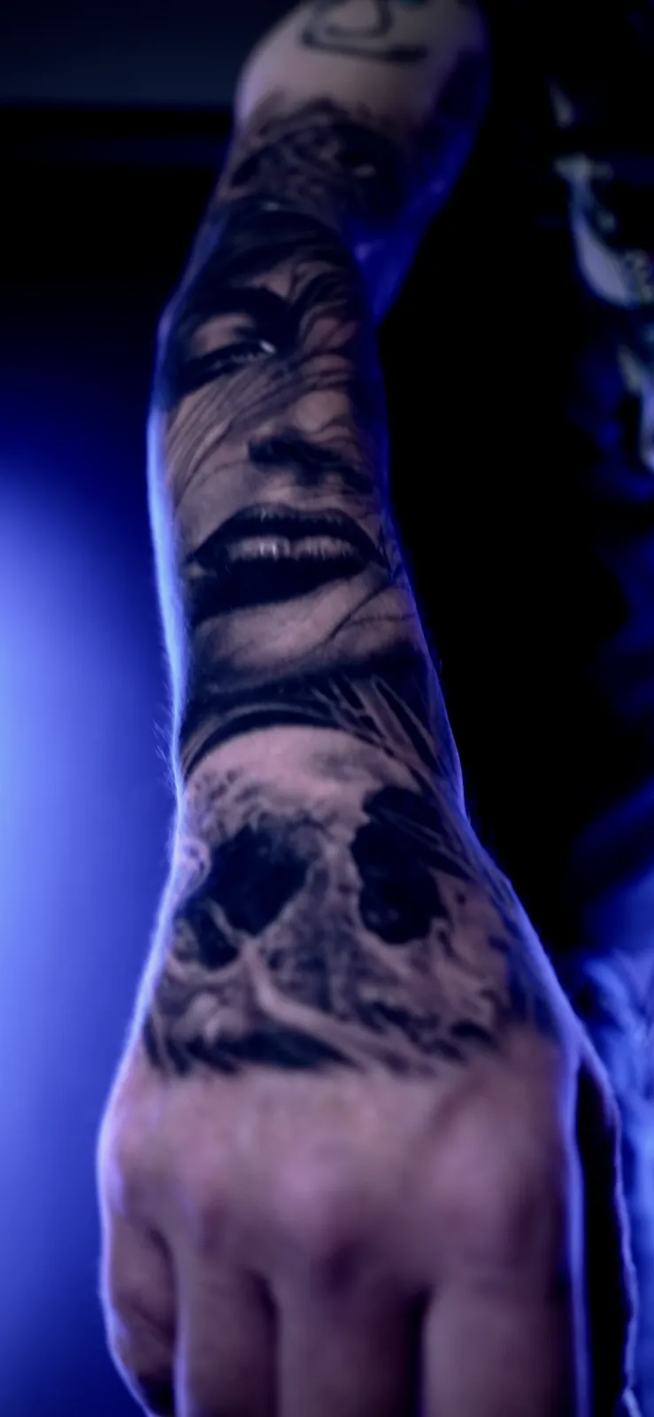 Black and grey portrait and skull hand tattoo